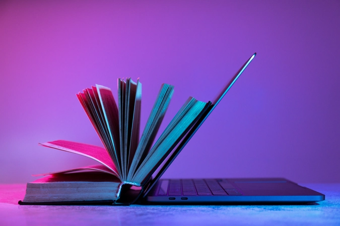 Digital Learning – Open book resting on laptop keyboard under neon purple and blue lighting, symbolizing fusion of traditional and modern education